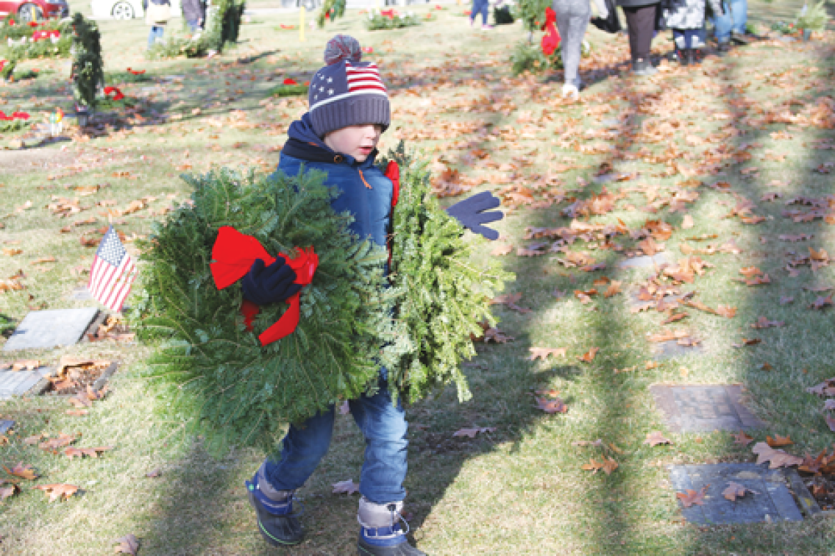  Noah Muckelvaney, 7, of Shelby Township, carries a few wreaths to be placed on the graves of veterans at Resurrection Cemetery in Clinton Township. The veteran tributes were part of Wreaths Across America’s event on Dec. 14. 