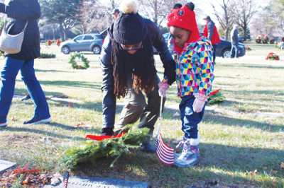  Pavi Elle Azeem helps Azura Azeem, 3, of Sterling Heights place a wreath on a veteran’s grave.  