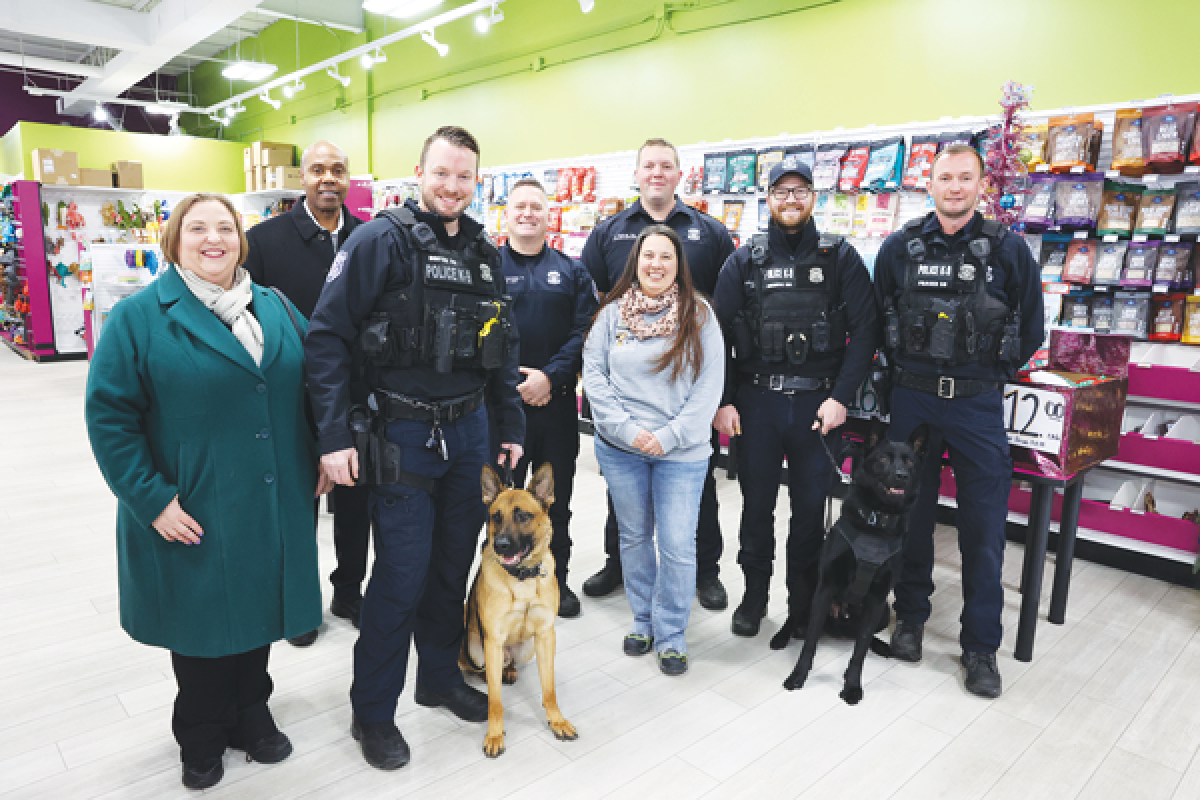  Mayor Lori Stone (left), Warren Police Commissioner Eric Hawkins (left, in the second row) and the Warren Police Department K-9 unit join Jill Tack (center), the owner of the Pet Beastro, to thank her for donating food and supplements to the department’s working and retired K-9s.  