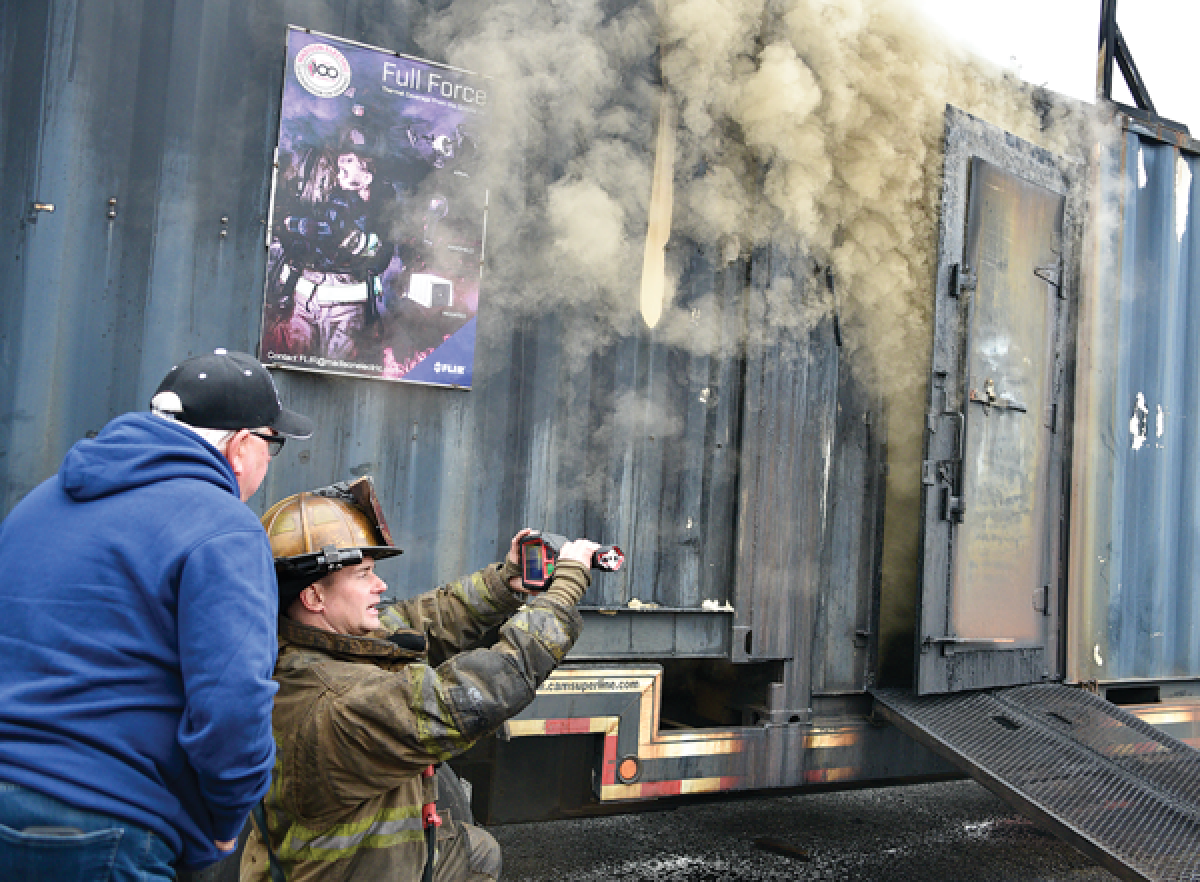  Warren City Councilman Dave Dwyer and Joe Schehr, the training coordinator for the Warren Fire Department, use the Seek camera to determine the conditions inside the box.  