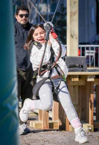  Ellie Huerta, 8, of Novi, takes a ride on the zip line during the 2024 Winter Blast. This year, the zip line will be hovering over Centennial Commons at 34 feet high, stretching 300 feet long.  