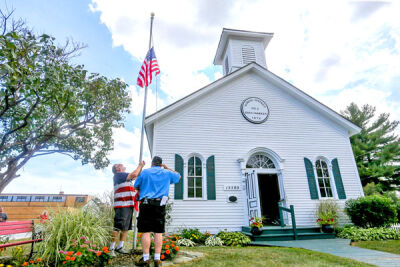  Jerry Hitchcock and Chris Pixley raise the new flag at the Halfway Schoolhouse in Eastpointe. 