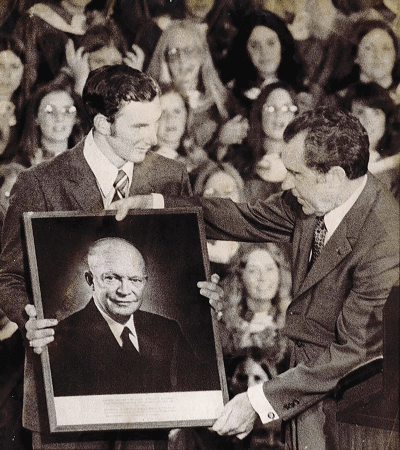  Eisenhower High School senior high school council President William Hellebuyck holds a photo of former President Dwight D. Eisenhower with President  Richard Nixon at the school’s dedication ceremony Aug. 24, 1972. 